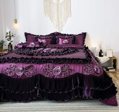 a bed with purple comforter and pillows in a room