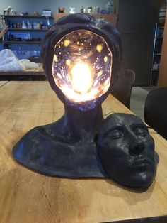 a sculpture on a table with a light in it's head