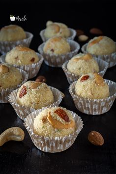 several muffins with nuts and almonds on a black counter top in paper wrappers