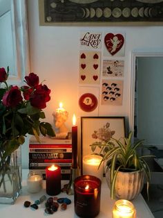 candles and flowers on a table in front of a window with valentine's day cards