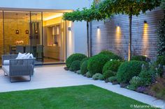 an outdoor living area is lit up with lights and greenery in the foreground