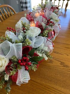 the table is set for christmas with candles and flowers on it, along with other holiday decorations