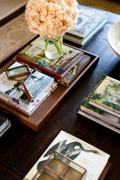 a wooden table topped with books and a vase filled with flowers on top of it