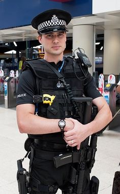 a police officer standing in an airport with his arms crossed and looking at the camera