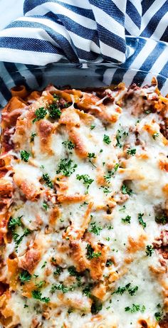 a cheesy casserole dish with meat and parsley on the top