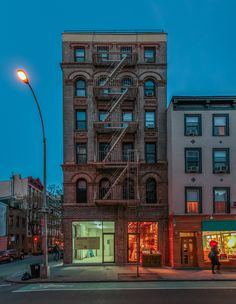 an old brick building on the corner of a street at night with a fire escape