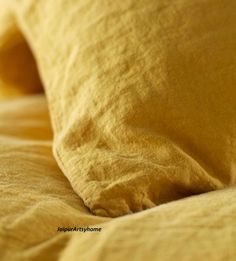 a close up view of a bed with yellow sheets and pillow cases on top of it