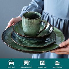 a woman holding a green coffee cup and saucer on top of a stack of plates