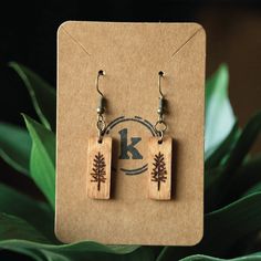 the earrings are made out of wood and have small trees on them, as well as letters