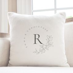 a white pillow sitting on top of a couch with a monogrammed r on it