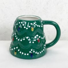 a green ceramic mug with designs on the outside and inside, sitting on a white surface