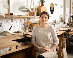 a woman sitting at a desk with lots of crafting supplies