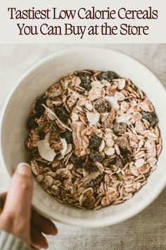 a person holding a bowl of granola in their hand with the words, tastiest low calorie cereals you can buy at the store