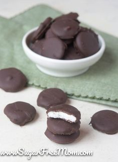 chocolate covered marshmallows in a white bowl on a green towel next to a napkin