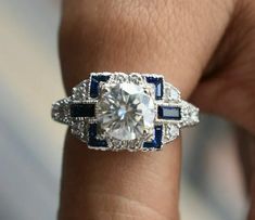 a woman's engagement ring with an old cut diamond surrounded by blue and white stones