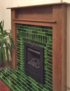 a fireplace with green tiles and a potted plant