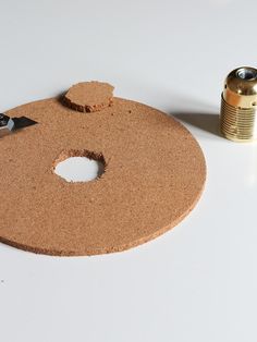 a cork board with a hole in the middle next to a can of soda and a pair of scissors