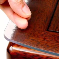 a close up of a person's hand holding a piece of wood on top of a table