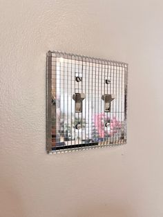 a mirror mounted to the side of a wall next to a metal wire frame with three lights on it