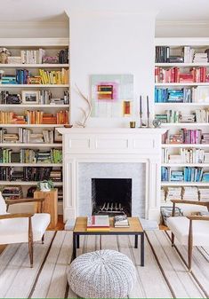 a living room filled with furniture and a fire place in front of a bookshelf