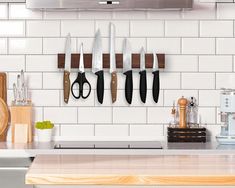 a kitchen counter with knives hanging on the wall and cutting board in front of it