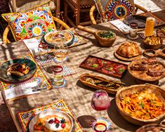 a table full of food and drinks on top of a wooden table covered in colorful cloths