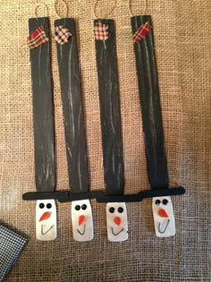 three snowmen made out of wooden sticks sitting on top of a table next to other items