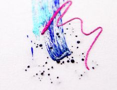 two different colored crayons are on the white paper with black and pink thread