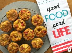 some muffins are on a wire rack next to a tea towel that says good food good life