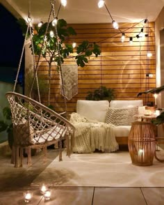 an outdoor living area with lights strung from the ceiling and hanging plants on the wall