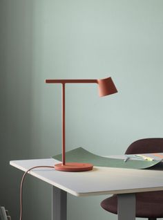 a desk lamp sitting on top of a white table next to a brown chair and green wall