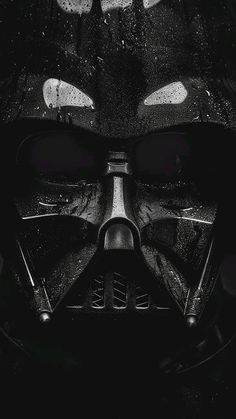 a black and white photo of a darth vader helmet with glowing eyes in the dark