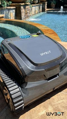 a robotic pool cleaner sitting on top of a wooden table next to a swimming pool