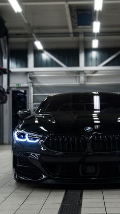 a black car parked in a garage with lights on it's headlamps