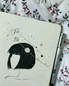 an open notebook with a drawing of a penguin and planets on the cover next to a pen