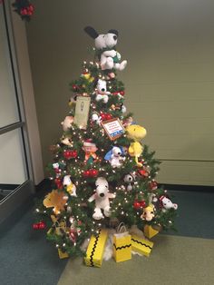 a christmas tree with stuffed animals and presents on it in an office cubicle area