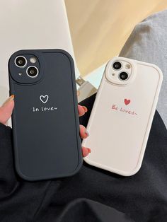 two cell phones that are sitting next to each other on a bed, one is black and the other is white