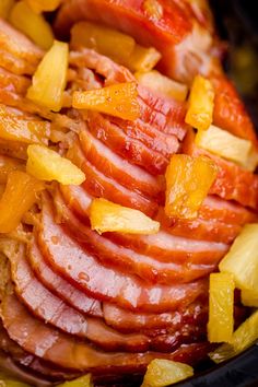 sliced ham and pineapples in a slow cooker with the meat ready to be cooked