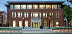 two people are standing in front of a building with many windows and lights on it