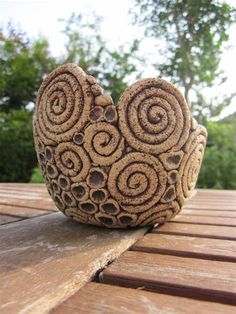 a close up of a decorative object on a wooden table with trees in the background