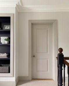 an empty room with a white door and some bookshelves