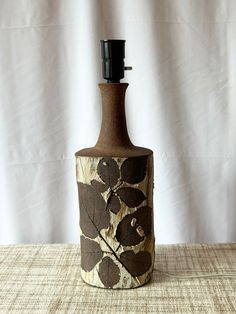 a brown and black vase sitting on top of a table next to a white wall