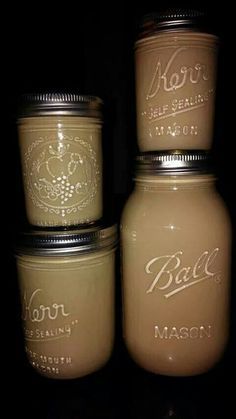 three mason jars with labels on them sitting next to each other in a dark room