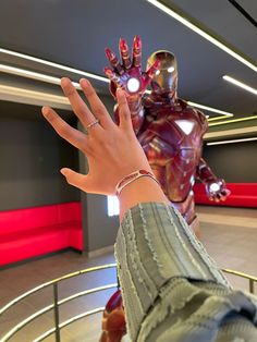 a person's hand reaching out towards an iron man in a room with red lights