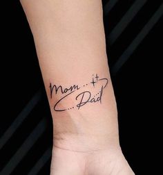 a woman's wrist tattoo with the words mom and dad written in cursive font