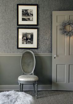 a chair sitting in front of two pictures hanging on the wall next to a door