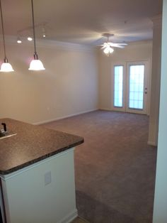 an empty kitchen and living room with granite counter tops on the island in front of the door