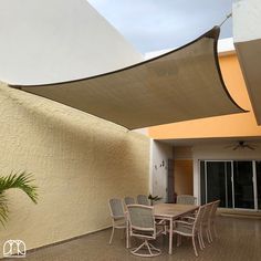 an outdoor dining area with table and chairs under a large awning over the patio