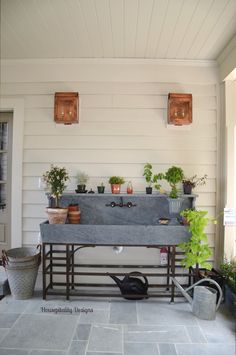 an outdoor sink with potted plants on the outside wall and hanging lights above it