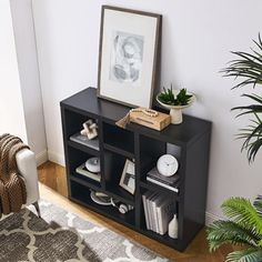 a black bookcase with books and pictures on it in a living room next to a chair